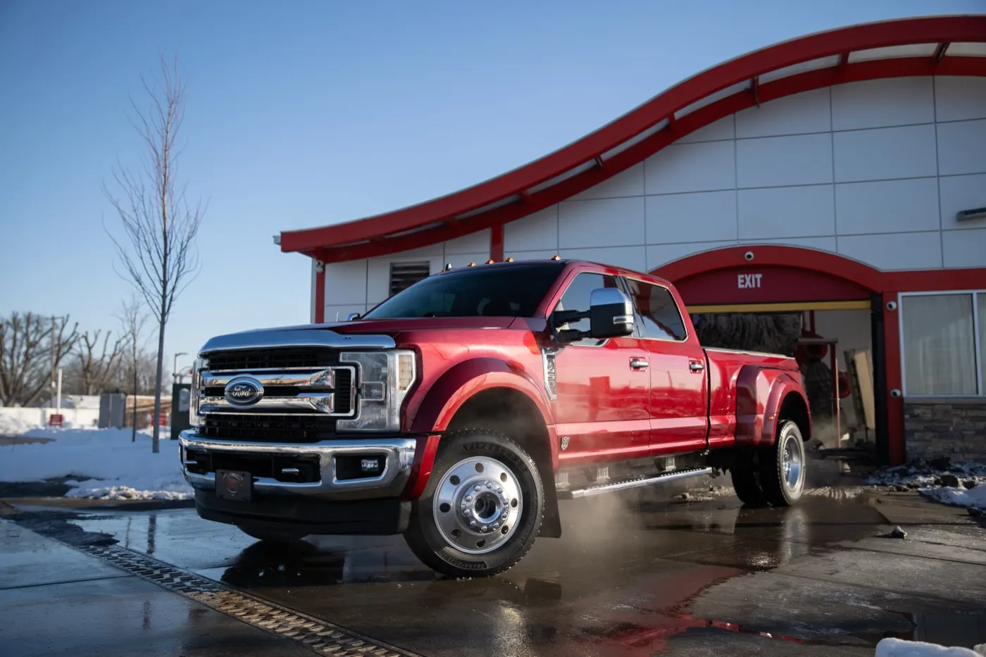 A freshly washed red Ford dually pickup leaving a Kopetsky Auto Wash